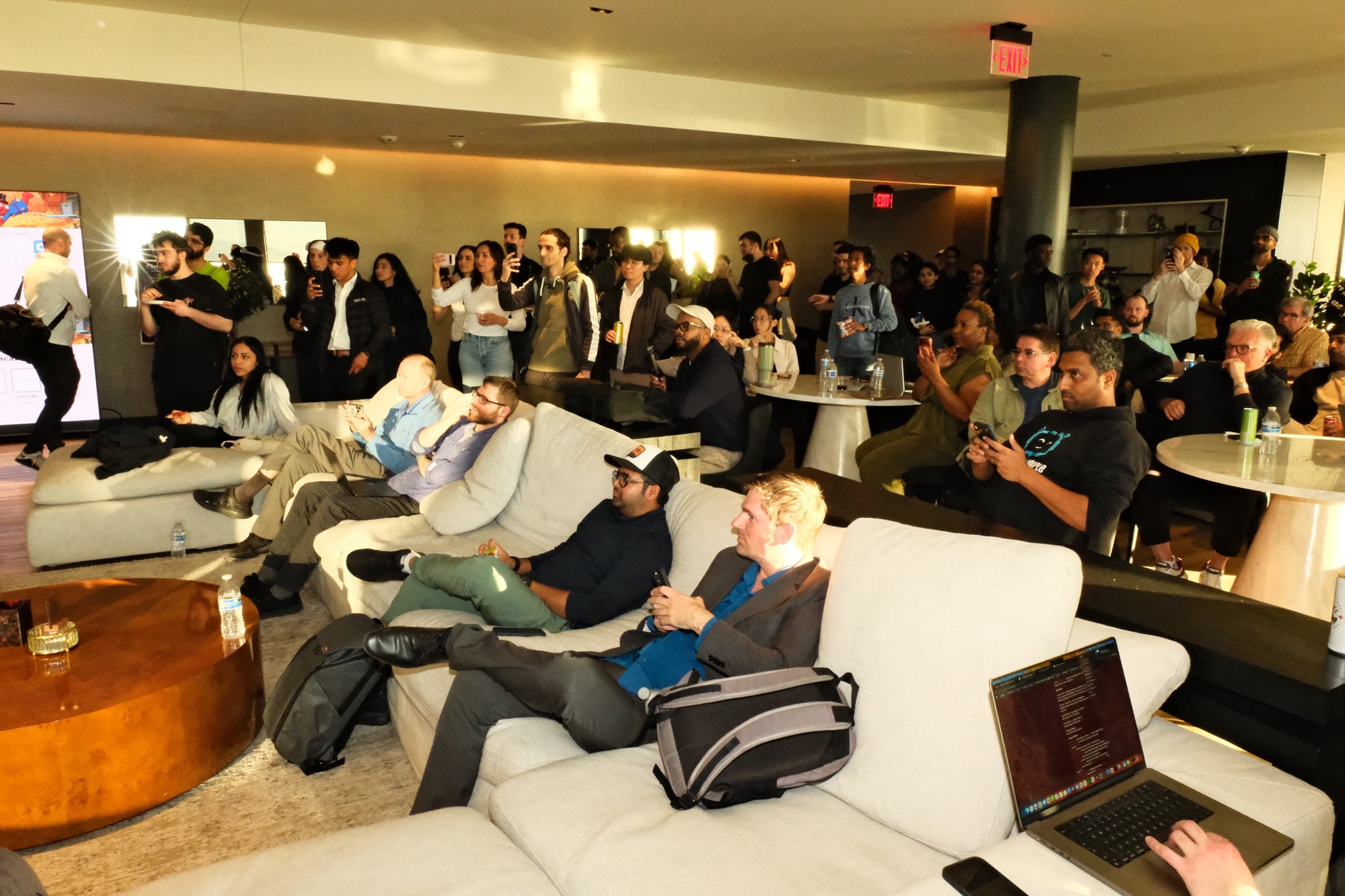 The full crowd watching the presentation at STAK, laptops open, phones recording